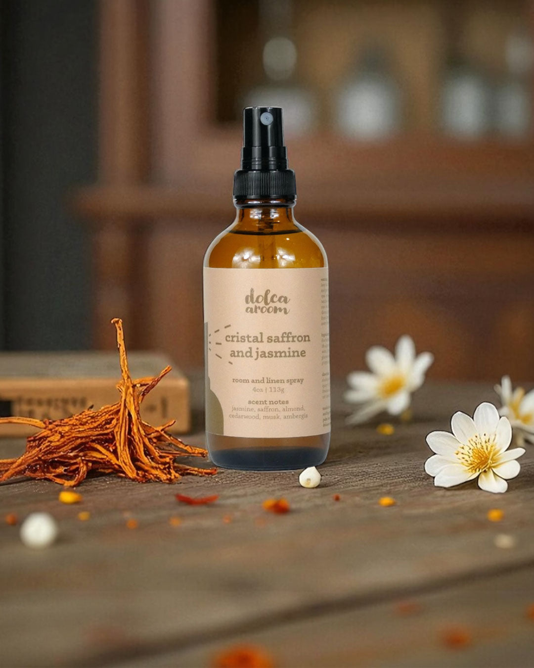 dolca aroom 4oz room and linen spray, cristal saffron and jasmine scent on a wooden surface with flowers and saffron strands.