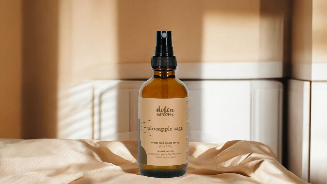 4oz bottle of dolca aroom room and linen spray, pineapple sage scent on a neutral linen sheet with a neutral background